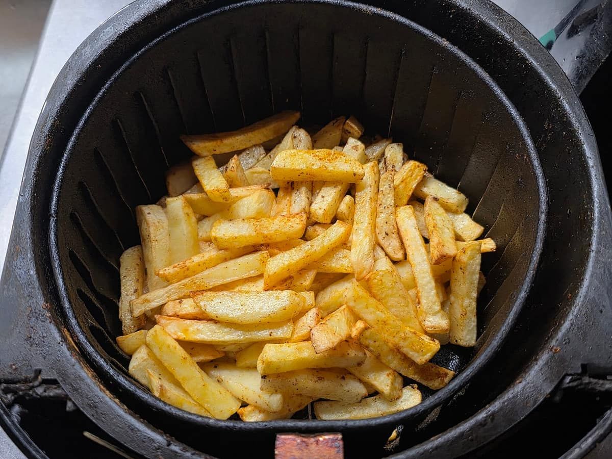 French fries cooked golden in the round basket of an air fryer