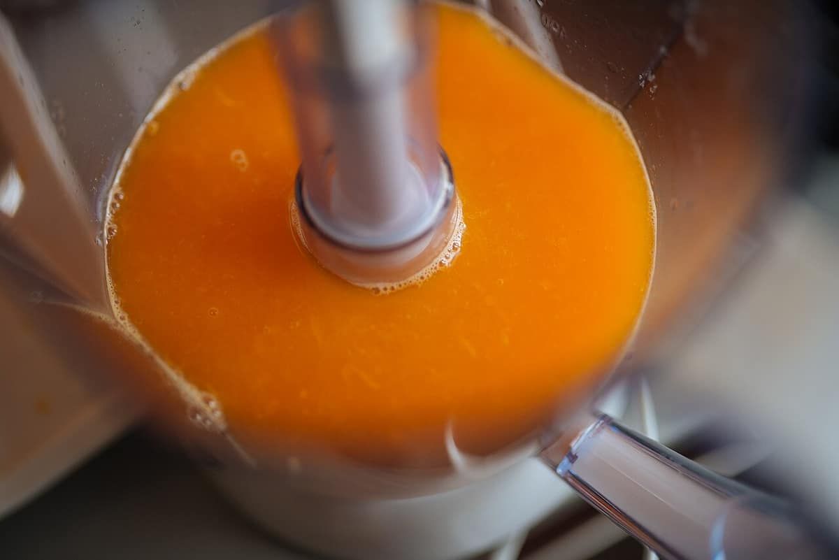 Looking down into a blender jar as orange juice blends around the central blade shaft