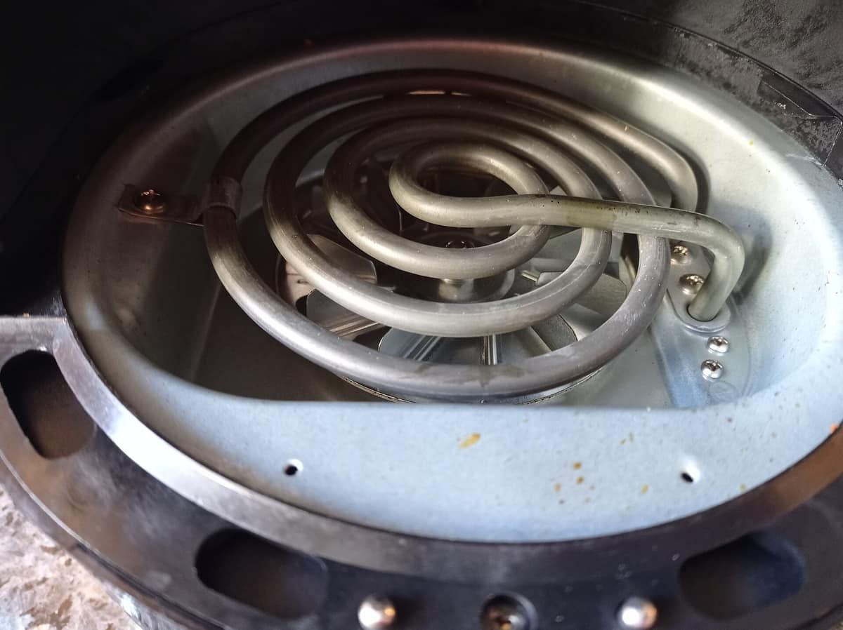 Looking up into an air fryer at the heating coil and fan above the basket