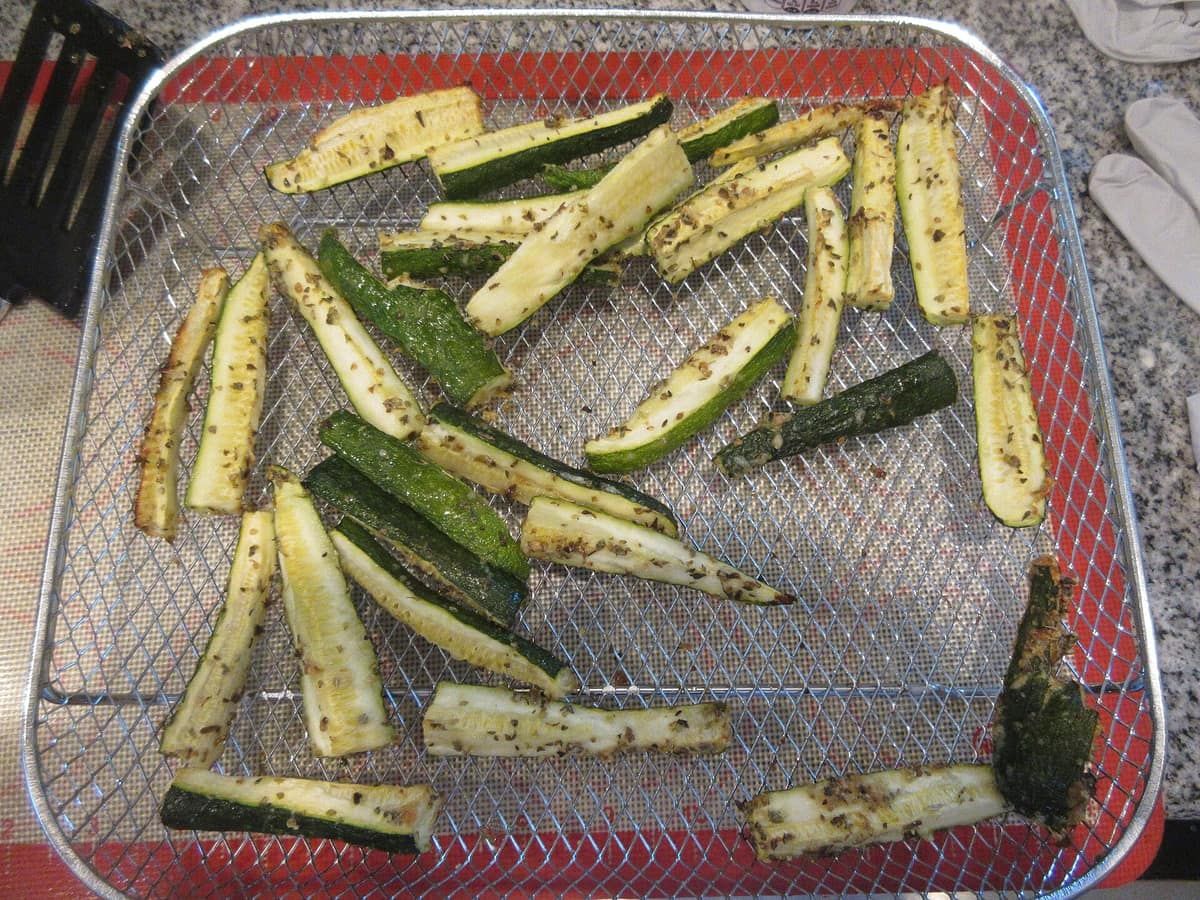 Sliced zucchini with herbs, air fried on a mesh tray until browned at the edges