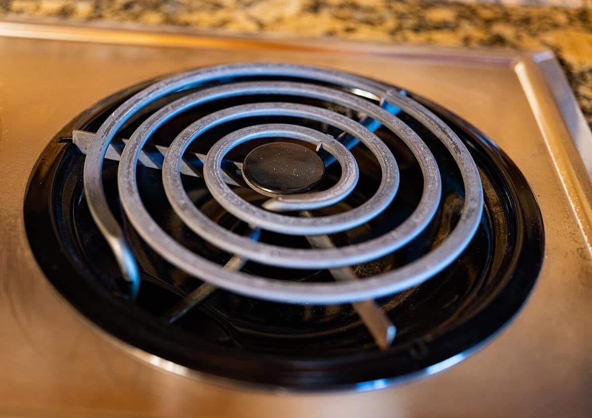 Close-up of a coiled electric stove burner set into a drip pan