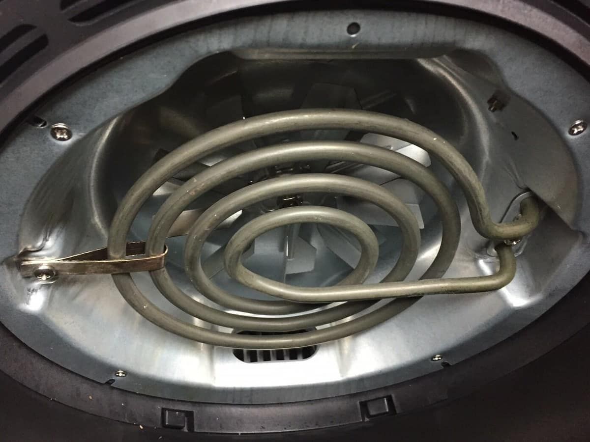 Looking up into an air fryer at the coiled heating element and fan guard above the basket
