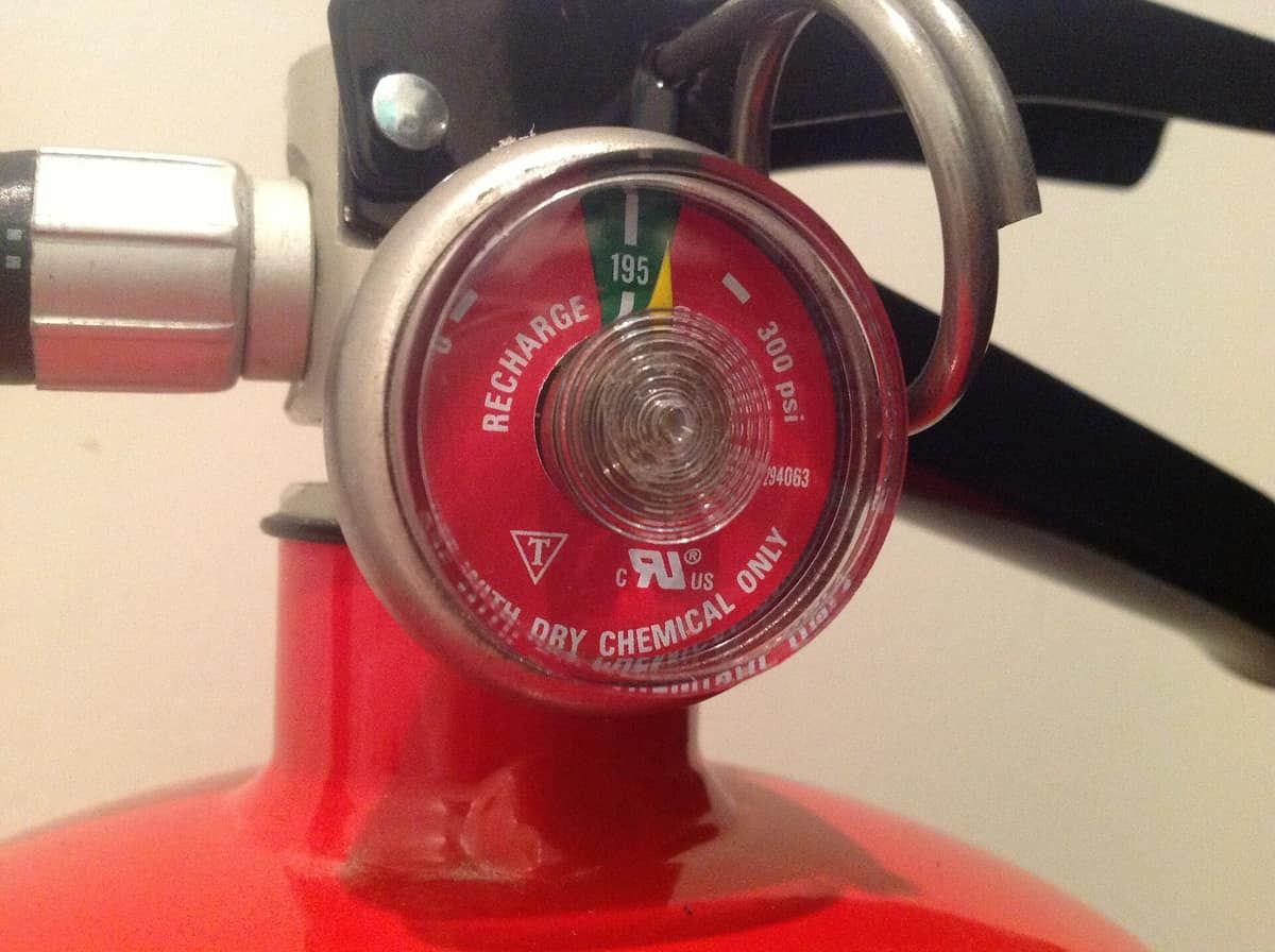 Close-up of the pressure gauge on top of a red dry-chemical fire extinguisher