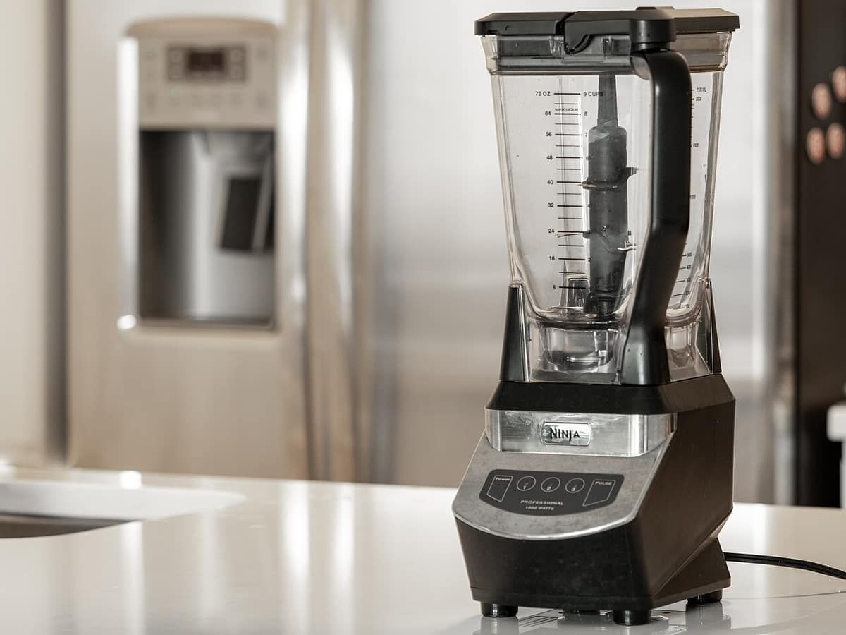 A black Ninja countertop blender with a tall clear pitcher on a kitchen counter
