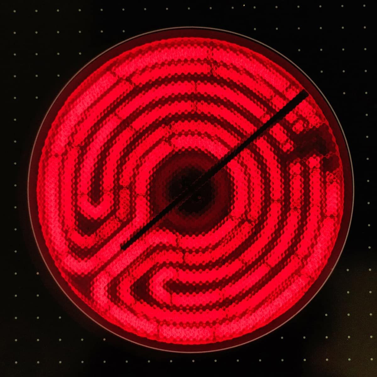 An electric stove element glowing bright red under a black glass cooktop